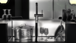 a kitchen sink with a pot and wine glasses